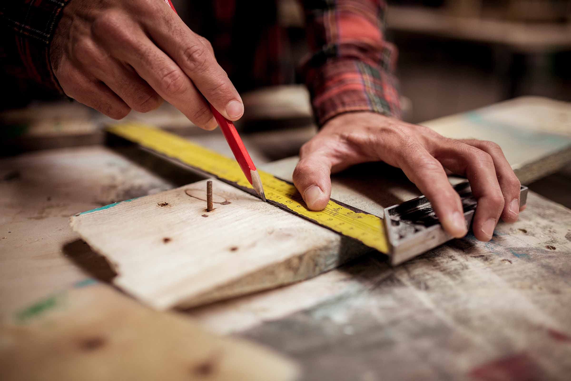 Cropped Image Of Carpenter Marking On Wood With Pencil