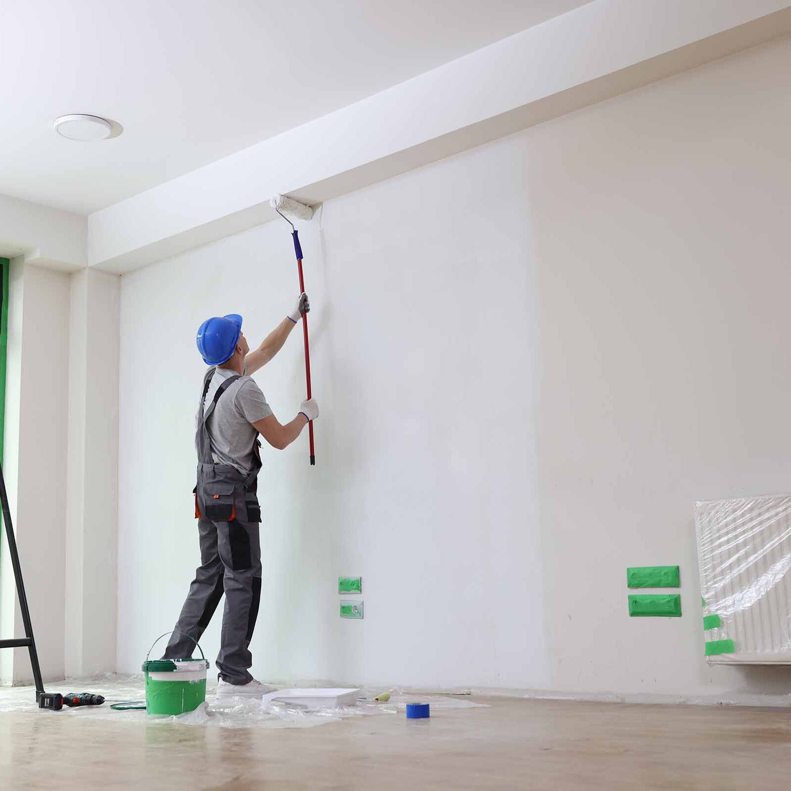 Male Painter Paints House Wall With Roller Brush.